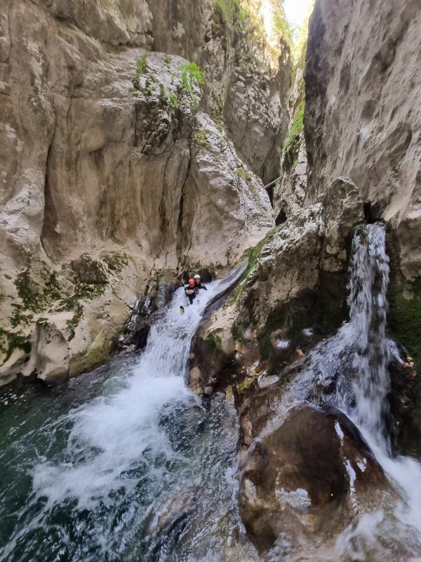 A guide instructing a first-time canyoner before a short abseil in a Montenegrin canyon