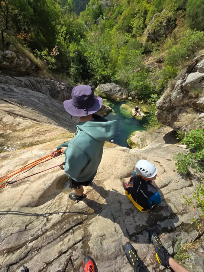 A guide rigging a rappel while a child waits their turn at the top
